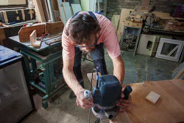 Carpenter using working tools while working on a wood in carpentry workshop