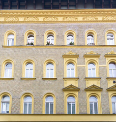 Obraz premium An old yellow brick house with beautiful stucco and flowers on the windowsills, in the historical center of Budapest, Hungary.
