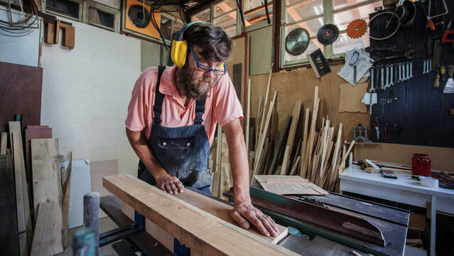 Carpenter using working tools while working on a wood in carpentry workshop
