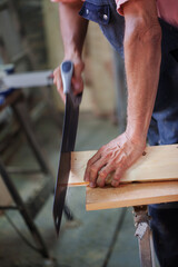 Carpenter using working tools while working on a wood in carpentry workshop