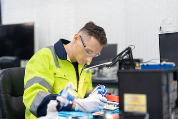 Male electrical engineer using digital multimeter checking voltage on microchip on board of automation robotic arm machine at factory