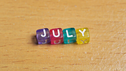 "July" word in colorful cubes. concept of months of the year, time. fun concept of time for kids