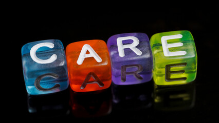 word "care" written in colorful cubes isolated on dark background. concept of caring and empathy for others. writing in colorful blocks with copy space area.