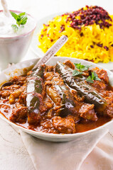 Traditional Persion lamb ragout xoresht-e badenjan with vegetable served with steamed saffron rice and berberis as close-up on a classic design plate