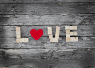 Love message written in wooden blocks and red heart on the grey wooden background
