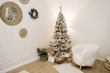 The house with a beautiful white interior is decorated for the new year, a Christmas tree and wreaths on the walls