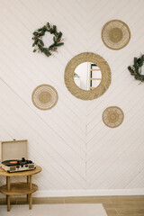 The interior of a beautiful bright house decorated for the New, white sofa, record player and wreaths on the walls