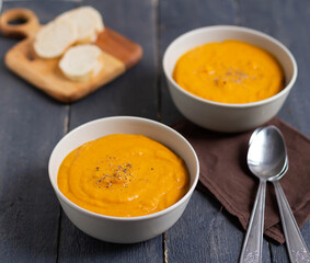 Two plates with pumpkin soup and spoons