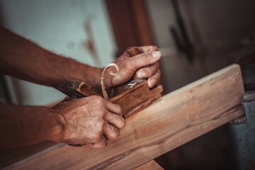 Carpenter using working tools while working on a wood in carpentry workshop