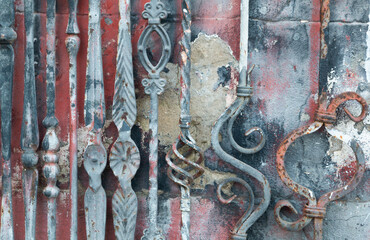 Wrought iron railing details in front of an old and worn painted wall. Old wrought iron