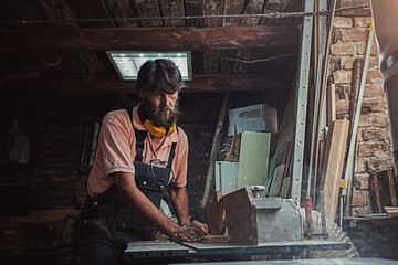 Fototapeta na wymiar Carpenter using working tools while working on a wood in carpentry workshop