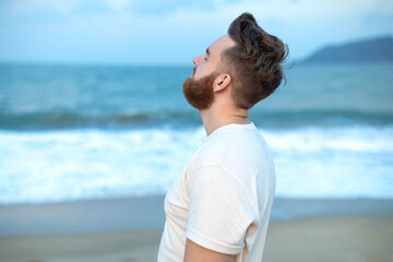 happy handsome free guy, young calm relaxed carefree man traveler enjoy sea on beach, ocean view, person feeling good, breath deep deeply fresh air. Freedom, travel, happiness concept, summer vacation