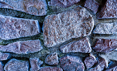 Wall of large stones. Abstract background from the surface of the stones covered with frost.
