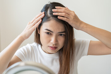 Damaged Hair symptom, face serious asian young woman, girl worry about balding, looking at scalp, hand in break into front hair loss, thin problem. Health care treatment for beauty concept.