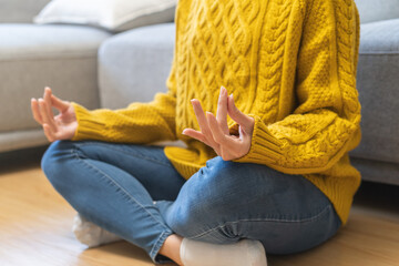 Beautiful asian young woman, girl hands in calm pose sitting practice meditating in lotus position on floor at home, meditation, exercise for wellbeing, healthy care. Relaxation, happy leisure people.