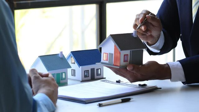 Real estate agents explain models of housing estates in projects to elaborate to clients, explaining and presenting information about homes and purchasing loans. Real estate trading concept.