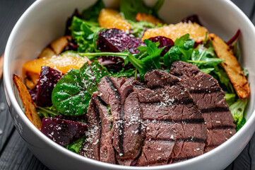 Salad with roast beef and caramelized beets with orange fillet, potatoes, parmesan, salad mix and olive oil