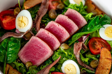 Salad Nisuaz with tuna, anchovies, potatoes, cherry tomatoes, salad mix, olive oil and quail egg