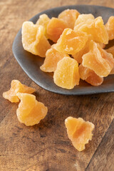 Candied melon pieces with sugar  on vintage plate on wooden background.