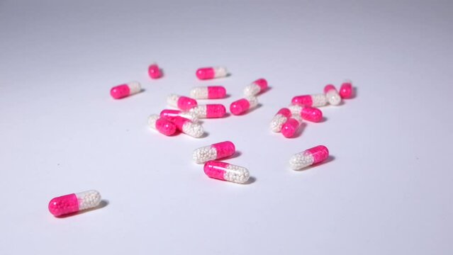 Group of the same pink medical pills, falls on white backgrounds, close up. Health care and medicine. Healthy lifestyle. Slowmotion.