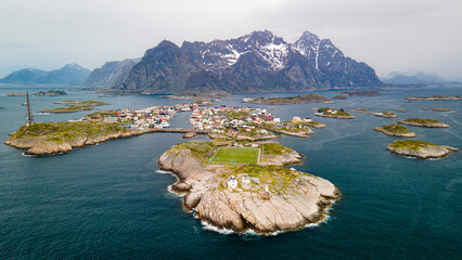 Aerial footage of Henningsvaer Stadium in Lofoten, Norway, during a sunny day with clouds