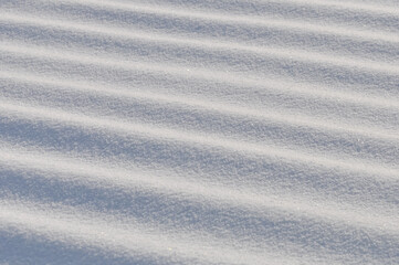 Snow lies in waves in a cold snowy winter, the play of light in straight lines