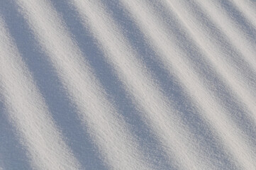 Snow lies in waves in a cold snowy winter, the play of light in straight lines
