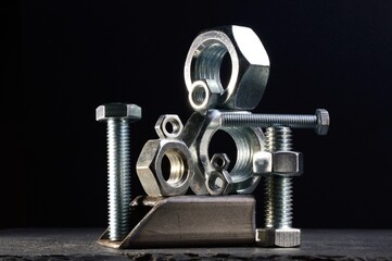 composition of nuts bolts and scraps of metal laid out on a dark background.