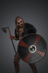 Fototapeta na wymiar Studio shot of redhead nordic warrior from past holding shield and axe.