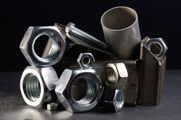 composition of nuts bolts and scraps of metal laid out on a dark background.