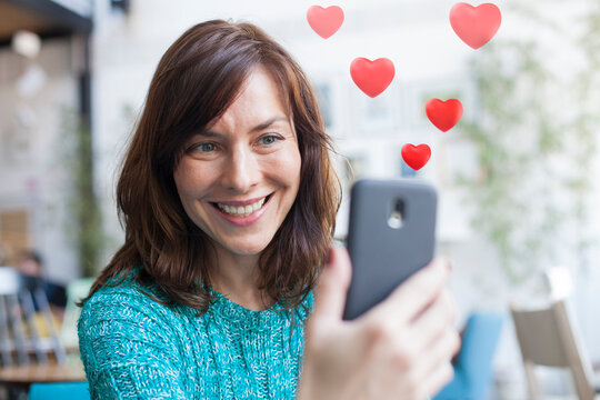 beautiful woman taking selfie with hearts coming out