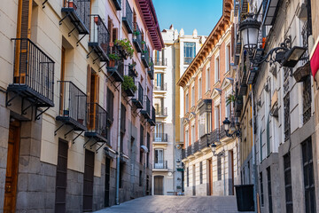 Fototapeta na wymiar Picturesque alley with old buildings, windows and terraces with bars in the city of Madrid, Spain.