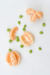 closeup the bunch ripe sliced orange fruit with green peas on the white background.