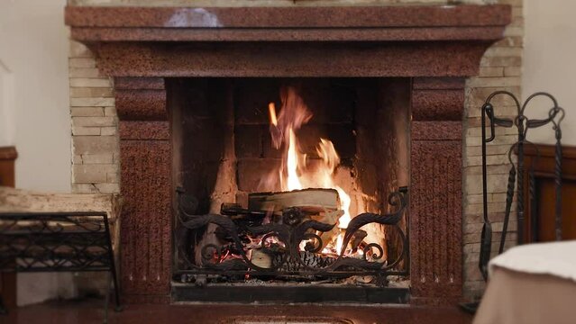 Fire burning in a fireplace in country cottage. Flame and firewood in fireplace.