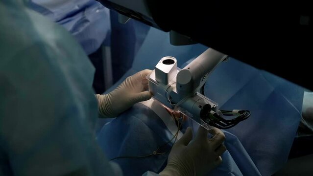 Ophthalmological surgery specialist sits in front of microscope performing operation.. Femto Assisted laser vision correction.