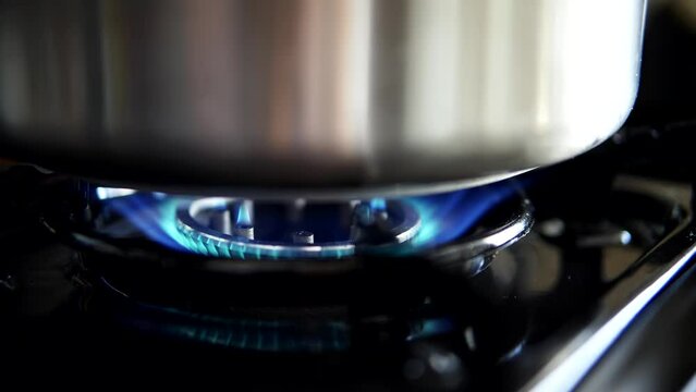 A blue flame fueled by gas burns on the kitchen burner