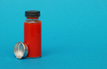 Glass vial for injections on a blue background.