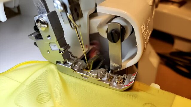 Sewing machine foot sewing yellow fabric in super slow motion