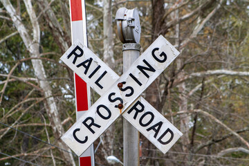 Vintage crossing signal, crossbuck at railroad crossing. Traffic signal with trees with leafless...