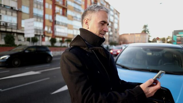 mature man with gray hair charging his electric car in the city