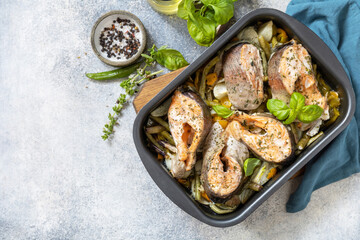 Healthy baked fish salmon steaks with basil, green beans, sweet peppers and onions. Cooking a delicious low carb dinner, healthy nutrition concept, diet menu. View from above. Copy space.