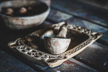 Interior of a Slavic traditional house from early medieval times. Dugout wooden spoon and carved tray. Wooden bowl and walnuts in the background. Table with kitchen utensils. Medieval kitchenware. 