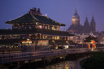 Fototapeta na wymiar Chinese restaurant at night with cathedral in the background, Amsterdam, Netherlands