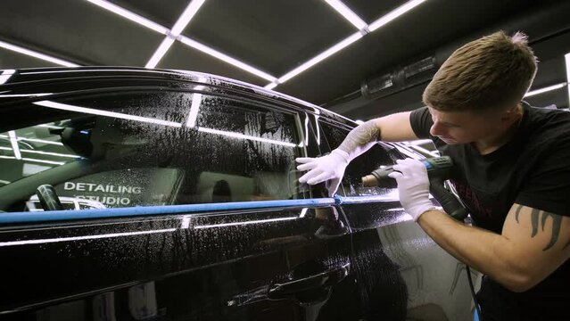Man covering car with vinyl polyurethane tape. Films for the car. Sticker protective film on the car