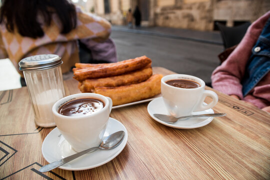 Tray of churros and two cups of chocolate on the terrace table, ready to eat the traditional Spanish churros in the bar.