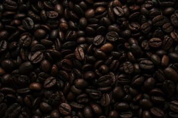 Beautiful background of roasted coffee beans. View from above. Coffee beans lie in a continuous carpet forming a wallpaper or coffee background.