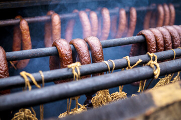 Homemade sausages in a traditional smoker smoked sausage and fish in Smokers. Traditional food. Smoked sausages meat hanging in domestic smokehouse. Fish of cold/hot smoked. Smoked Fish In Smokehouse.