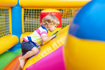 Fototapeta na wymiar Happy kid having fun on colorful inflatable attraction playground