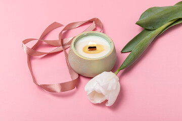 Handmade candle, white tulip and ribbon on pink background. Gift for Women's Day or Mother's Day