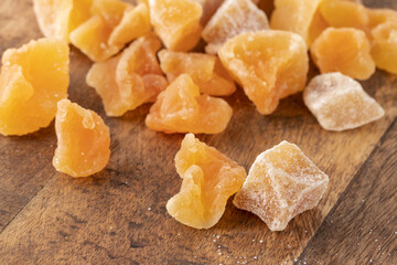 Candied melon pieces with sugar scattered on wooden background.
